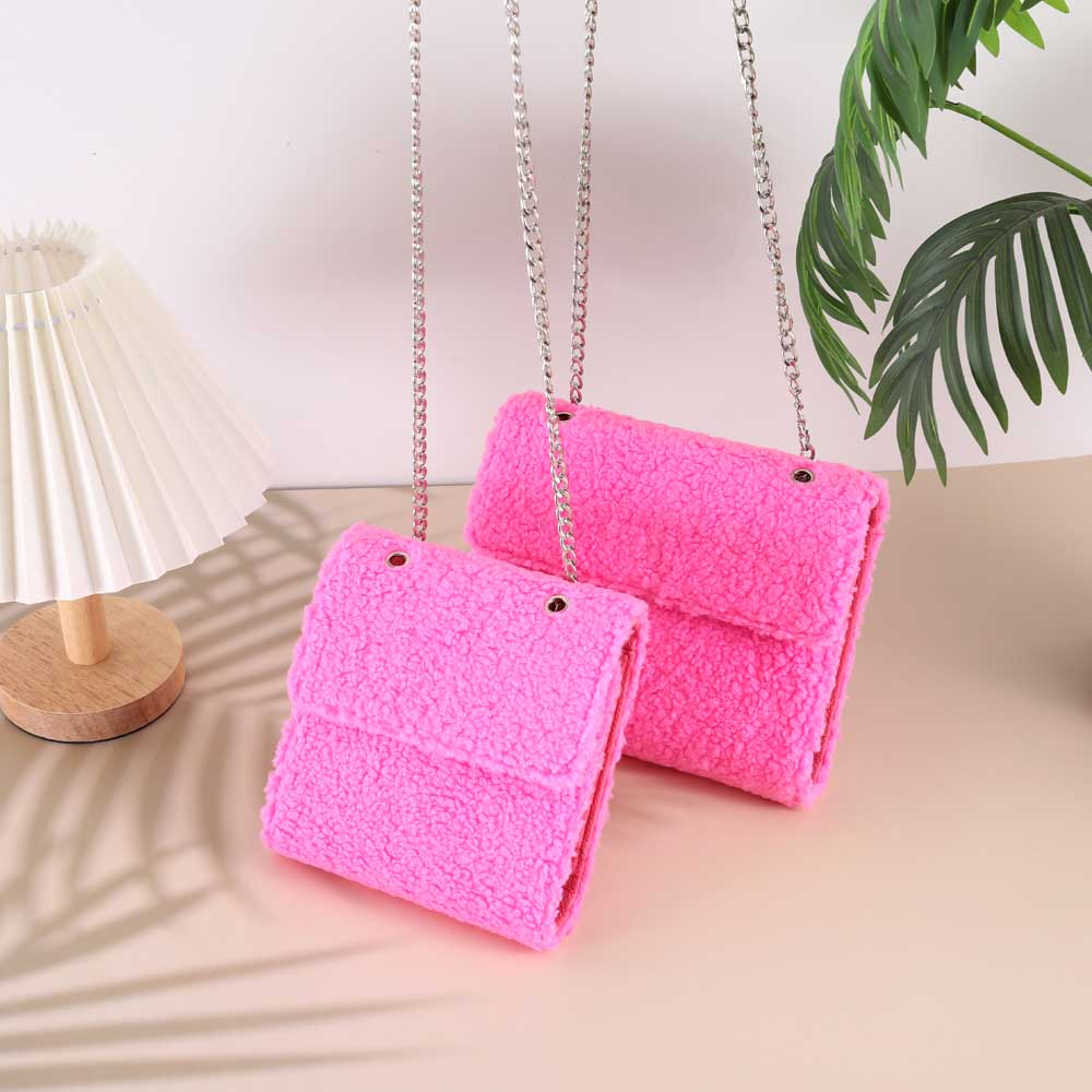 A6 and A7 hot pink sherpa teddy wallets from Baddies & Budgets shown together with silver chain straps, styled with a pleated lamp and palm leaves